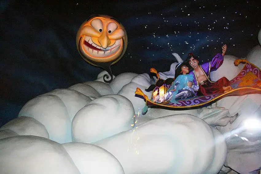 Personajes sobre nubes y sol riendo en la atracción Pasaje Aladín - Escena encantada