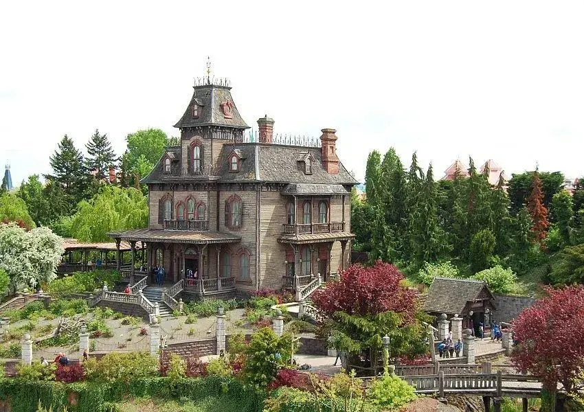 Vista lejana de la mansión Phantom Manor con visitantes esperando para entrar - Aventura fantasmagórica 