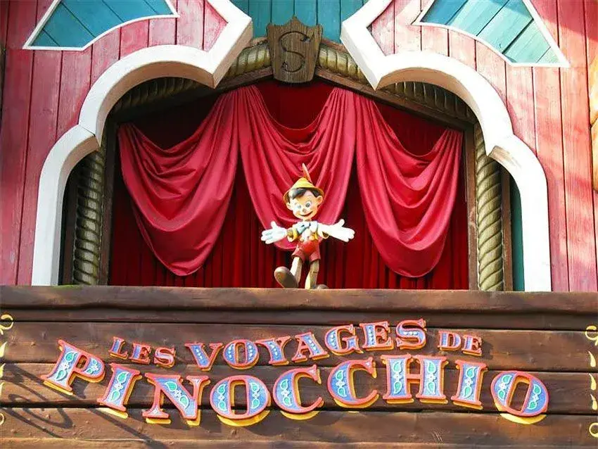 Cartel con el nombre Les Voyages de Pinocchio y la figura de Pinocho haciendo un gesto de bienvenida en Disneyland Paris