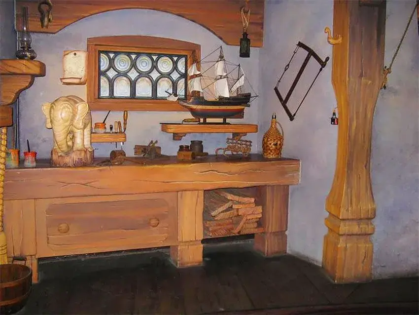 Detalle del interior de la atracción Les Voyages de Pinocchio en Disneyland Paris, con una mesa de madera y creaciones artísticas