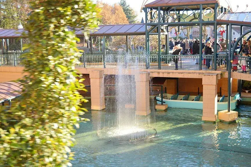 Fuente de agua y visitantes en un puente listos para entrar a It's a Small World