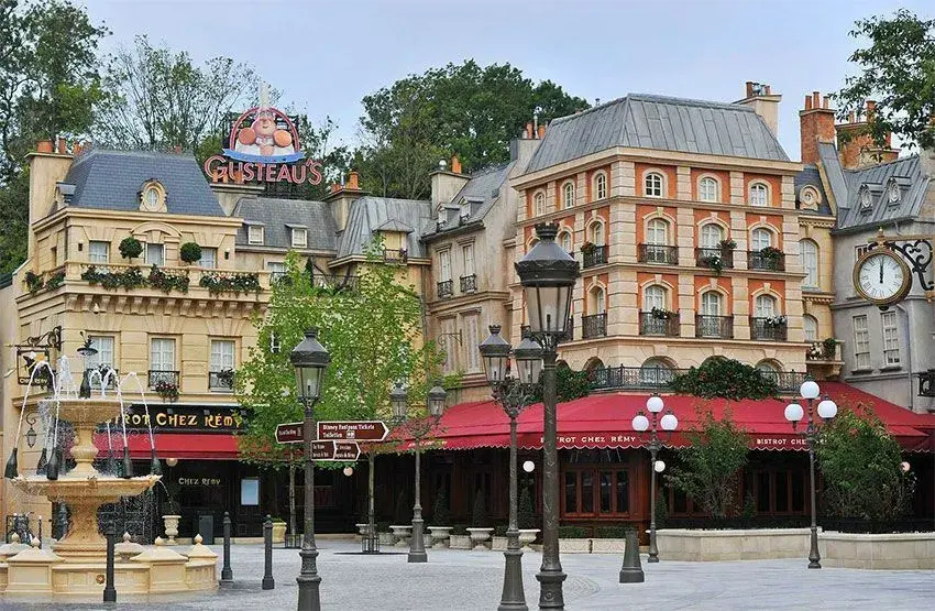 Vista lejana del Bistrot Chez Rémy rodeado de árboles y faroles temáticos