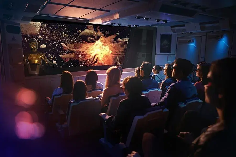 Personas observando una pantalla temática de Star Wars dentro de la atracción, simulando una experiencia de cine