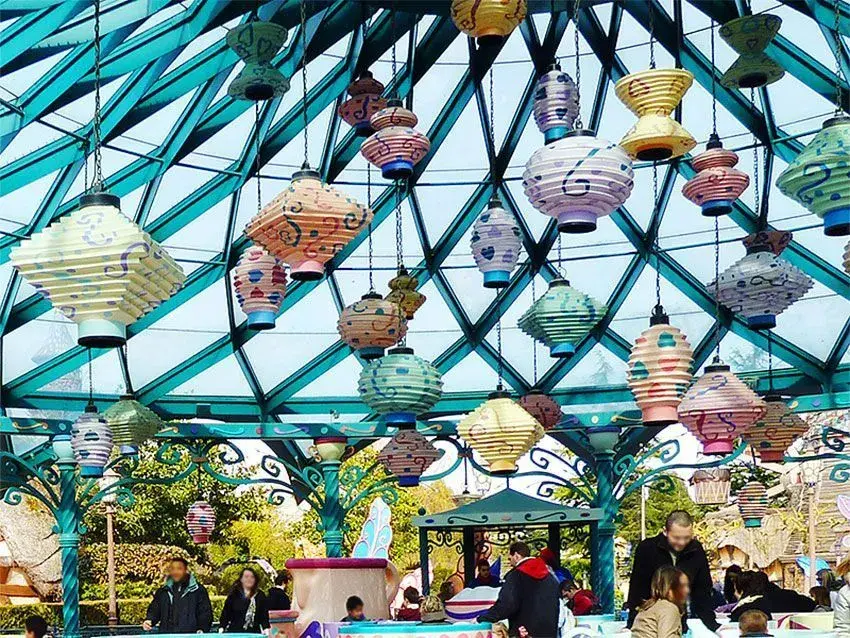 Visitantes disfrutando de la atracción Tazas Locas, con tazas suspendidas y niños sonriendo mientras giran.