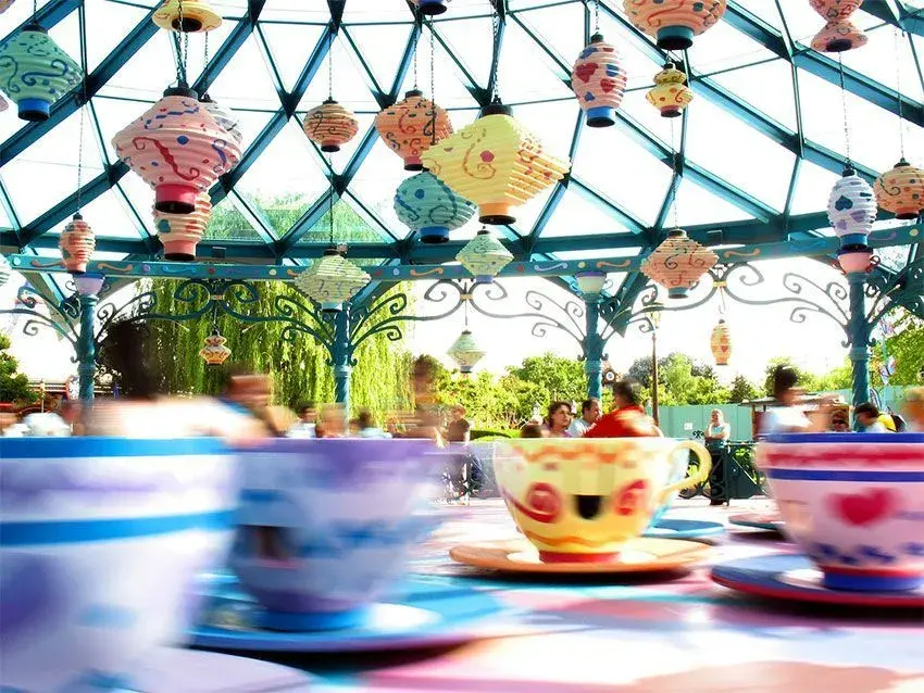 Tazas locas en pleno movimiento, con niños montados y disfrutando de la experiencia en Disneyland Paris.