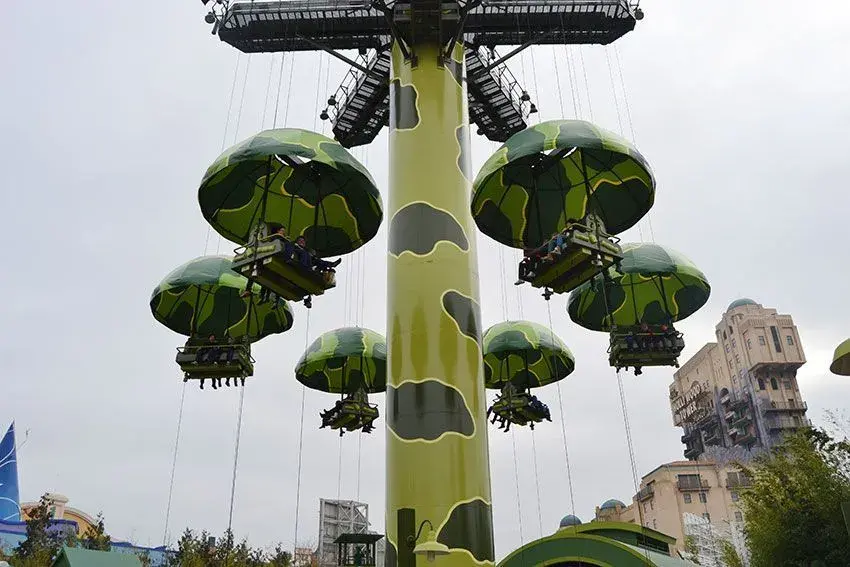 Sombrillas voladoras con estética militar en Toy Story Playland, personas disfrutando de la atracción aérea