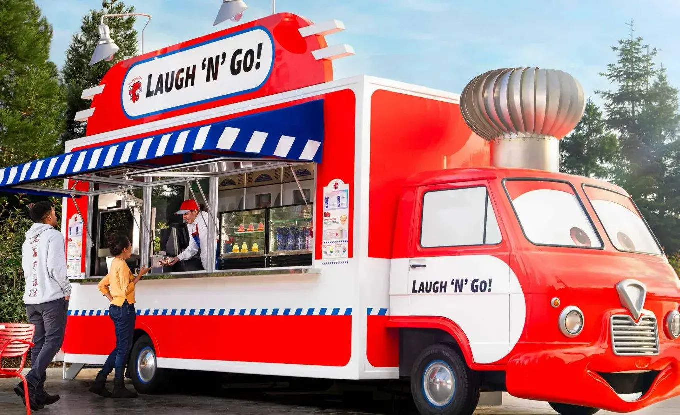 Puesto de snacks Laugh’n’Go! en Disneyland Paris, inspirado en Cars ROAD TRIP, con bebidas y bocados temáticos como el Croque McQueen y cupcakes Pixar. 🚗🍔